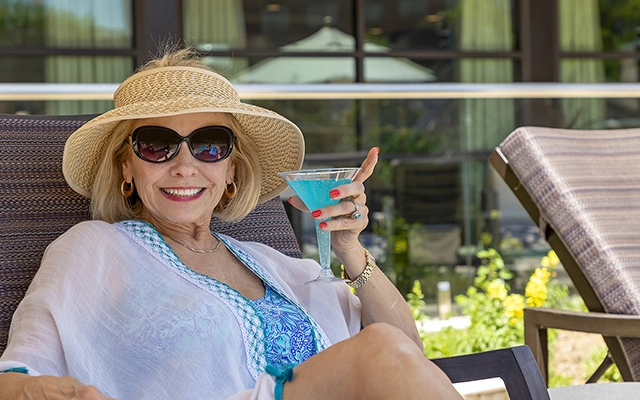 Senior female resident drinking a cocktail by the pool